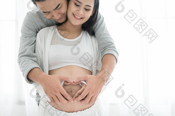亚洲美丽的怀孕了女人英俊的丈夫拥抱肚子爱夫妇手使<strong>心怀</strong>孕了肚子