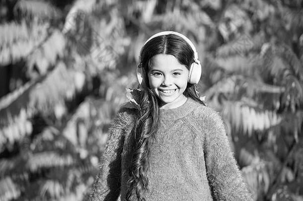 音乐适合秋天的心情。小女孩戴着耳机在秋树旁休息。聆<strong>听歌</strong>曲。欣赏秋天的音乐。秋天伴着美妙的<strong>歌</strong>声漫步。儿童教育和可下载有声读物。