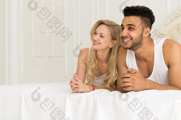 年轻夫妇躺在床上，<strong>幸福</strong>地微笑着，西班牙裔男女恋人在卧室里