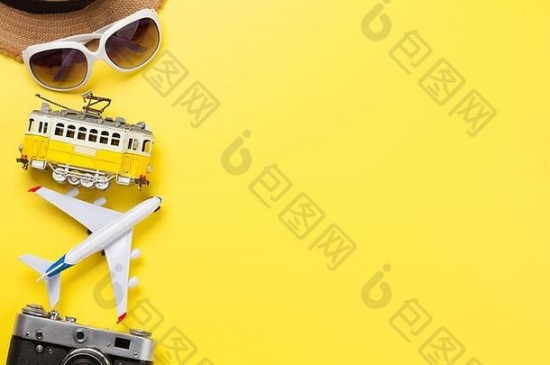 在黄色阳光背景下，配备照相机、太阳帽、太阳镜、有轨电车和飞机玩具的旅行概念。具有空间的俯视平面布局