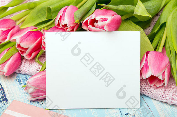 粉色郁金香花束，蓝色木质背景上的礼品盒和黑纸，空间。