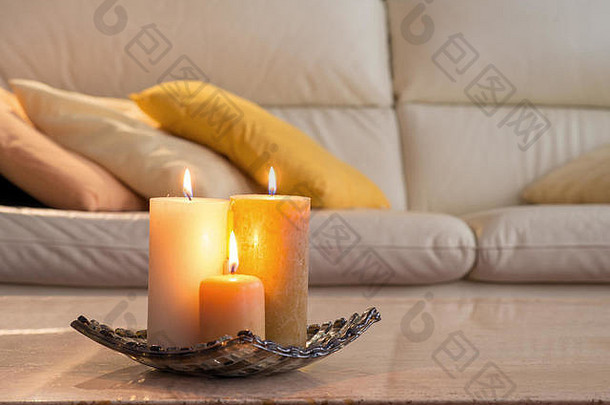 在大理石桌子上点燃蜡烛，背景是一张带枕头的沙发，这