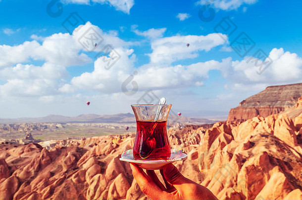 卡帕多西亚风景背景下的一杯土耳其茶。天空中的气球。