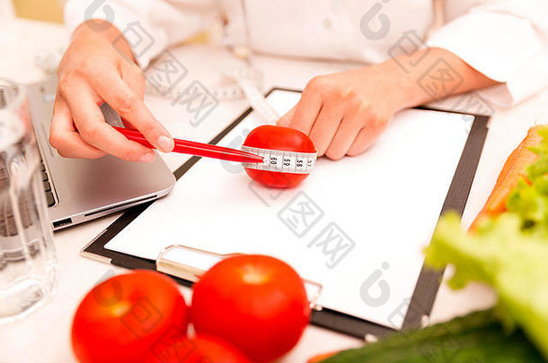 蔬菜饮食营养或药物概念。女营养师，桌上摆着蔬菜和卷尺