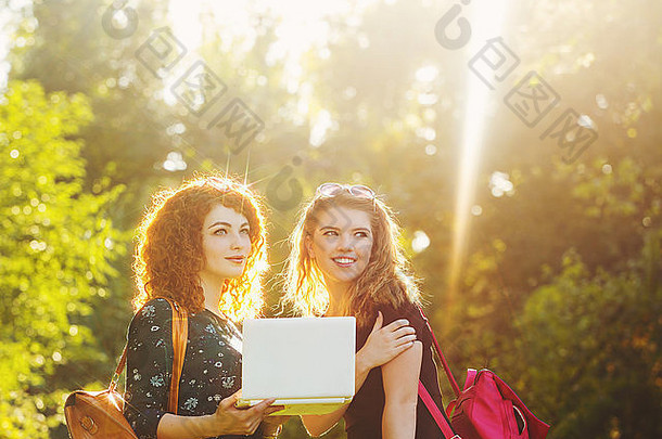 城市公园里的年轻女朋友。那个女孩拿着一本笔记本。社交网络。最好的朋友。