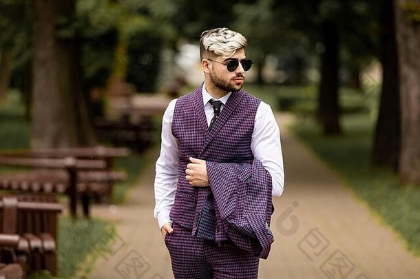 年轻的业务男人。太阳镜穿紫罗兰色的勒克斯三件套西装一边走街