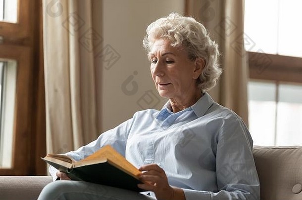 安详的中年妇女在家里读纸质书畅销书。