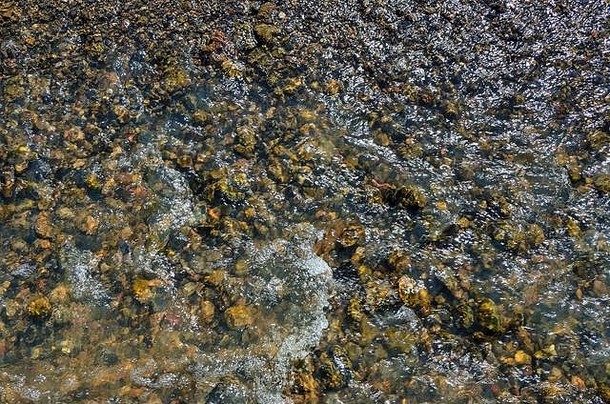清凉清新的山河在阳光明媚的夏日里湍急流淌。透明清澈的水面下五颜六色的鹅卵石，水面上阳光耀眼
