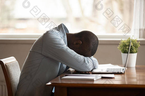 精疲力竭的混血男子在笔记本电脑前睡着了