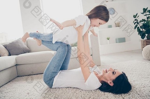 快乐可爱可爱的妈妈躺在地毯上抱着她的小孩想象她在客厅里像鸟一样飞