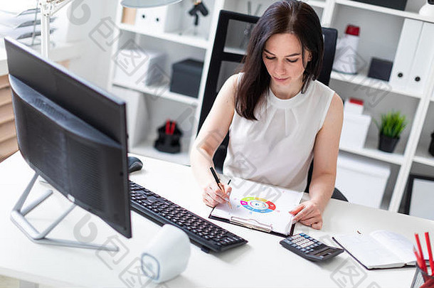 年轻的女孩坐着办公室电脑桌子上工作文档