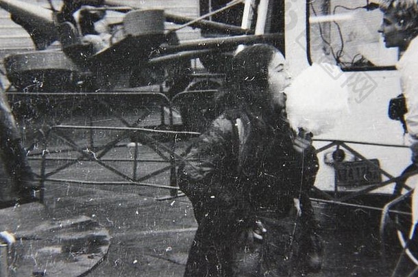 精美的70年代复古黑白生活摄影，一个女孩正在吃一团毛茸茸的棉花糖。