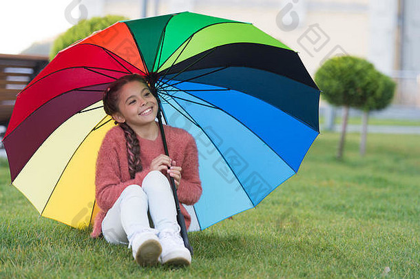 坐着伞有趣的小女孩公园等待雨色彩鲜艳的伞概念幸福彩虹感动了快乐小女孩微笑