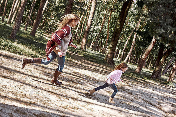 快乐、时尚的<strong>小卷发</strong>女孩和她美丽的母亲在森林里跑步