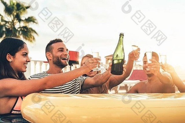 快乐朋友敬酒香槟池聚会，派对年轻的人有趣的喝闪闪发光的酒奢侈品热带海滩度假胜地日落