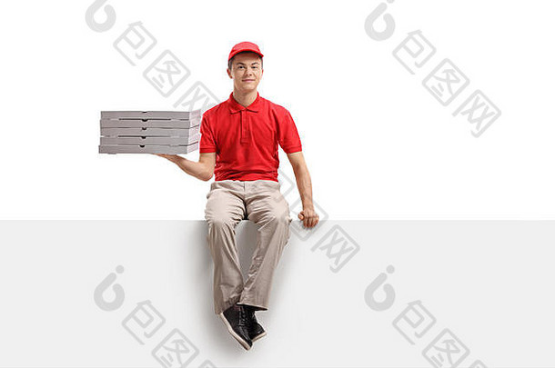 十几岁的比萨饼递送男孩拿着一堆比萨饼盒，坐在白色背景上的一块隔离板上