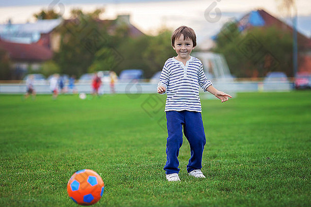 蹒跚学步的男孩玩足球足球有趣的在户外日落操场上活跃的孩子们秋天一天