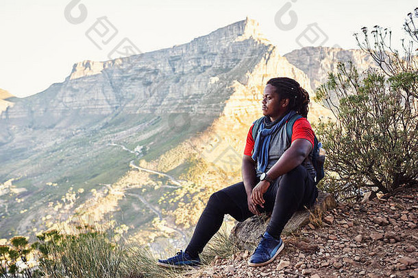 非洲徒步旅行者在一条山路上的徒步小道旁休息，欣赏周围群山的美景