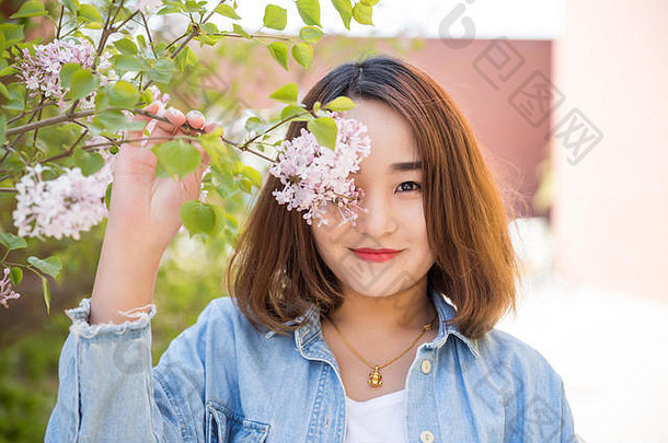 美丽快乐的年轻女子欣赏春花的户外肖像