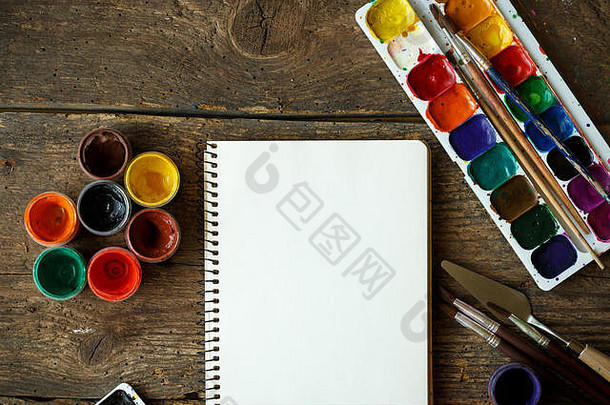 绘画艺术。绘画套装：纸、画笔、颜料、水彩、丙烯酸漆，木质背景自上而下