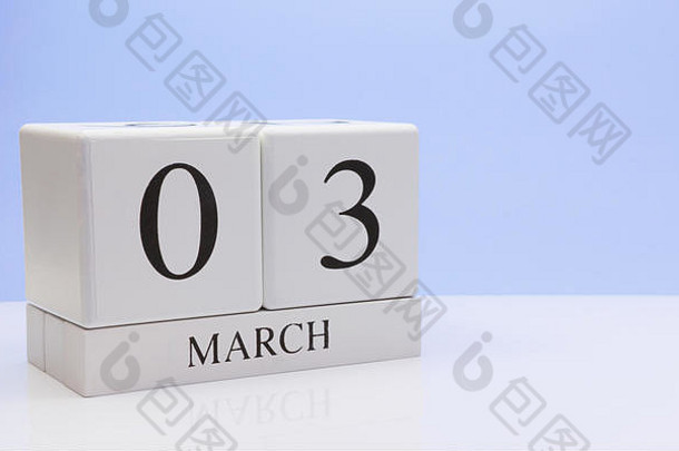 <strong>三月三</strong>号。月的第03天，日历在白色的桌子上反射，浅蓝色背景。春天，文本的空白