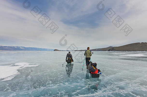 一个女人和一个男人带着雪橇和<strong>登山杖</strong>在贝加尔湖的蓝色冰面上