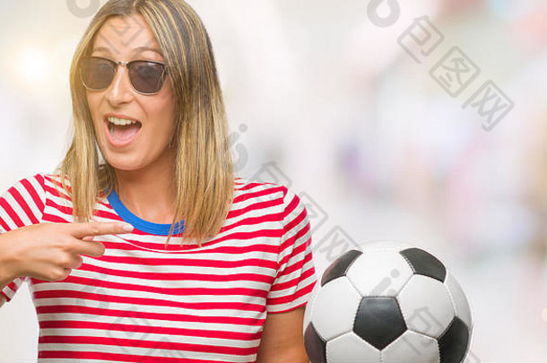 年轻的美丽的女人持有足球足球球孤立的背景快乐指出手手指