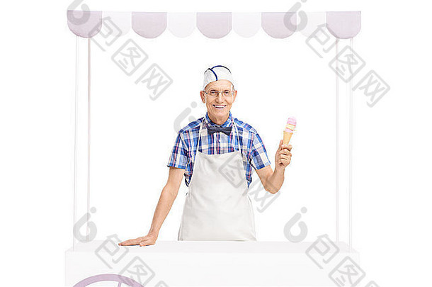 工作室拍摄的一个冰淇淋小贩拿着一个冰淇淋筒，在一个白色背景上孤立的摊位后面摆姿势