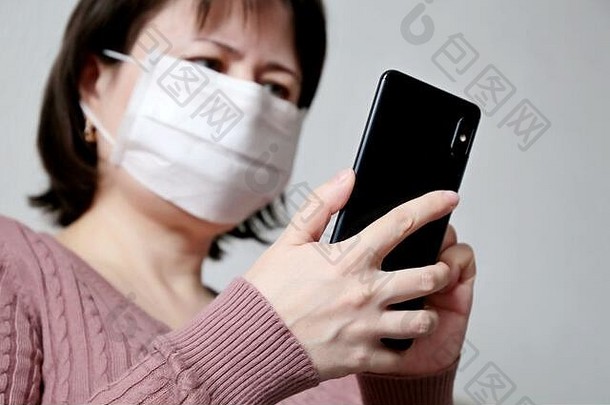 女人医疗面具智能手机特写镜头移动电话女手概念疾病发热冷流感搜索冠状病毒症状