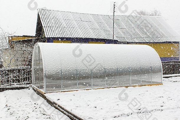 塑料温室位于地球上，覆盖着降雪