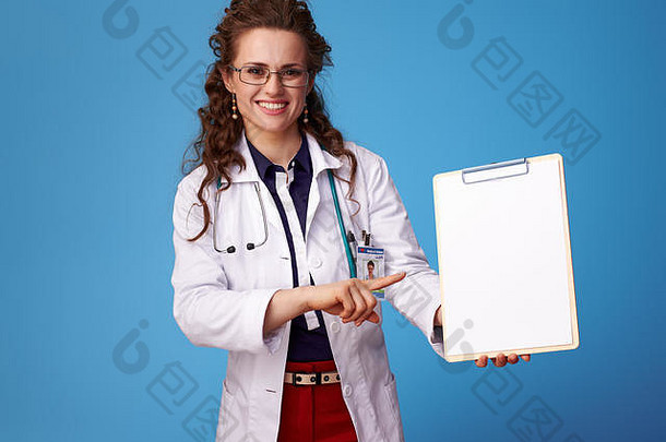快乐医生女人白色医疗袍指出剪贴板孤立的蓝色的