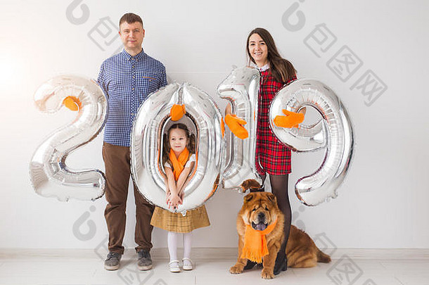 2019年的新概念即将到来——欢快的母亲、父亲、女儿和狗在室内手持<strong>银色</strong>数<strong>字</strong>。