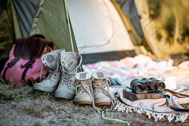 露营地，带帐篷、登山鞋、背包、森林中的格子布