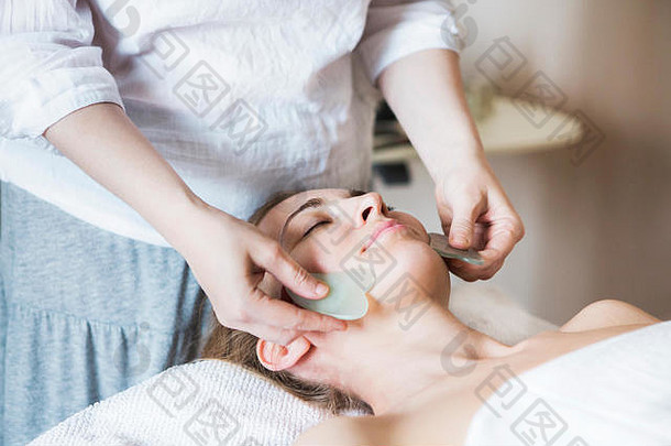 年轻的女人脸刮痧疗法治疗亚洲美诊所