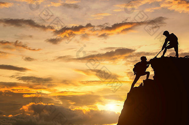 男女徒步旅行者爬上悬崖，其中一人<strong>伸出援助之手</strong>。帮助他人，团队合作的理念。
