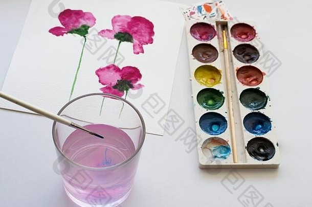 白色桌子上的粉红色木兰花和艺术工具的水彩画。艺术工作场所的静物构成