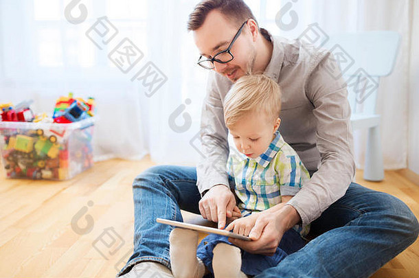 父亲和儿子在家玩平板电脑