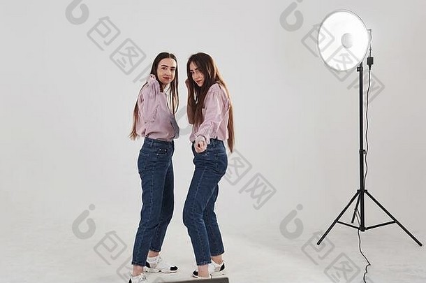 专业照明姐妹双胞胎站摆姿势工作室白色背景