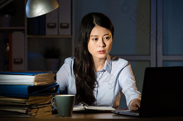 亚洲业务女人坐着桌子上工作移动PC加班晚些时候晚上在室内办公室背景