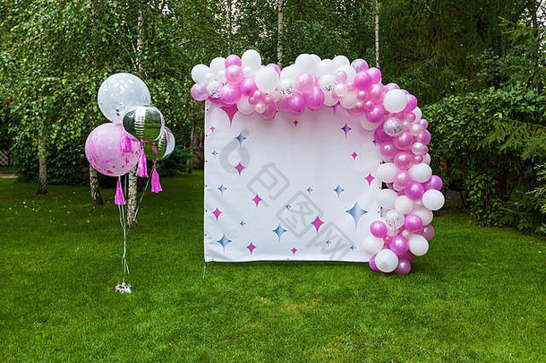 在大自然中庆祝生日的装饰，粉色气球和题字横幅。