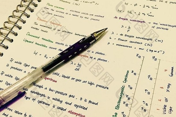 用彩色笔迹写的物理笔记，纸上有一支笔。