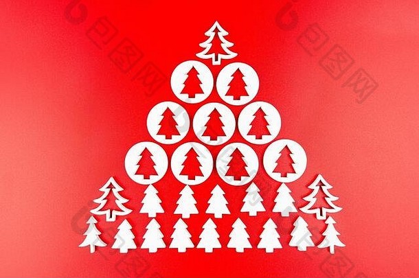 白色木材制成的木制圣诞树，呈大圣诞树的形状排列，与红色背景隔离。