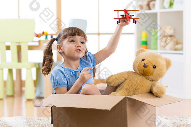 在托儿所里玩飞行员飞行纸板箱的小女孩