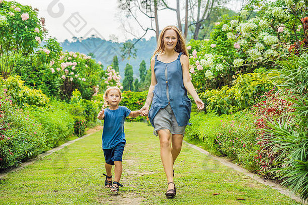 <strong>妈妈</strong>和儿子在盛开的花园里跑来跑去。幸福家庭生活方式理念