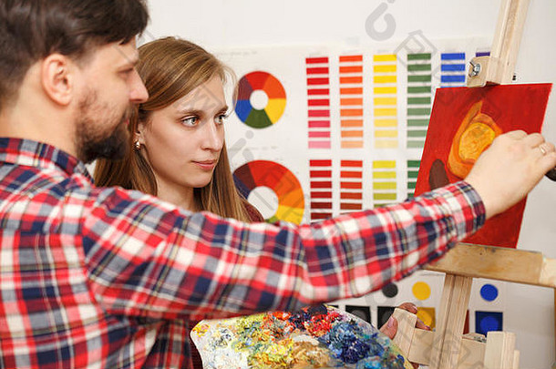 老师在美术学校观察学生绘画。一个人用调色刀和油画<strong>颜料画</strong>静物。成人绘画课程。
