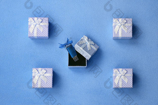 明亮的蓝色usb闪存卡和蓝结放在一个蓝色的小礼品盒里，小蝴蝶结放在柔软毛茸茸的浅蓝色羊毛毯上