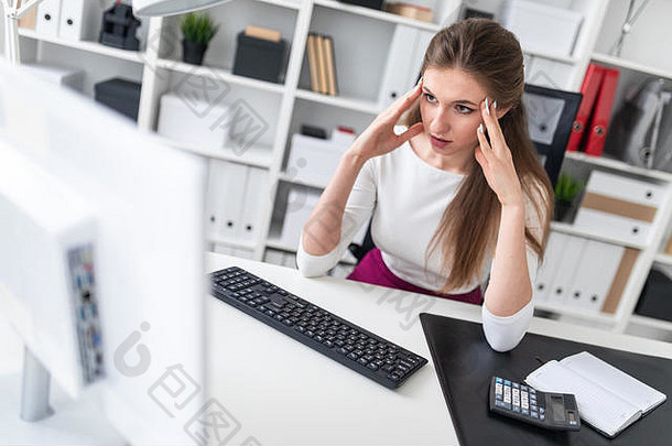 年轻的女孩坐着电脑表格持有手头