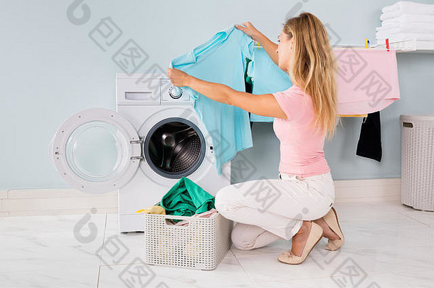 在<strong>杂物间</strong>的洗衣机里洗完衣服后看衣服的年轻女子