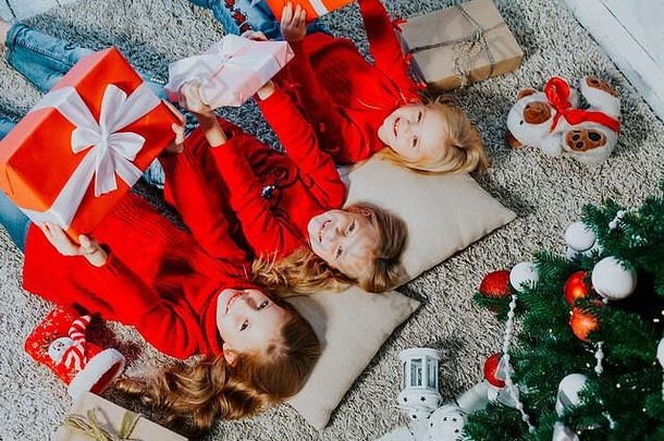 三个金发小女孩躺在地板上<strong>新年</strong>圣诞树礼物