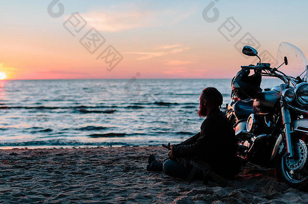 日落时海滩上的摩托车手